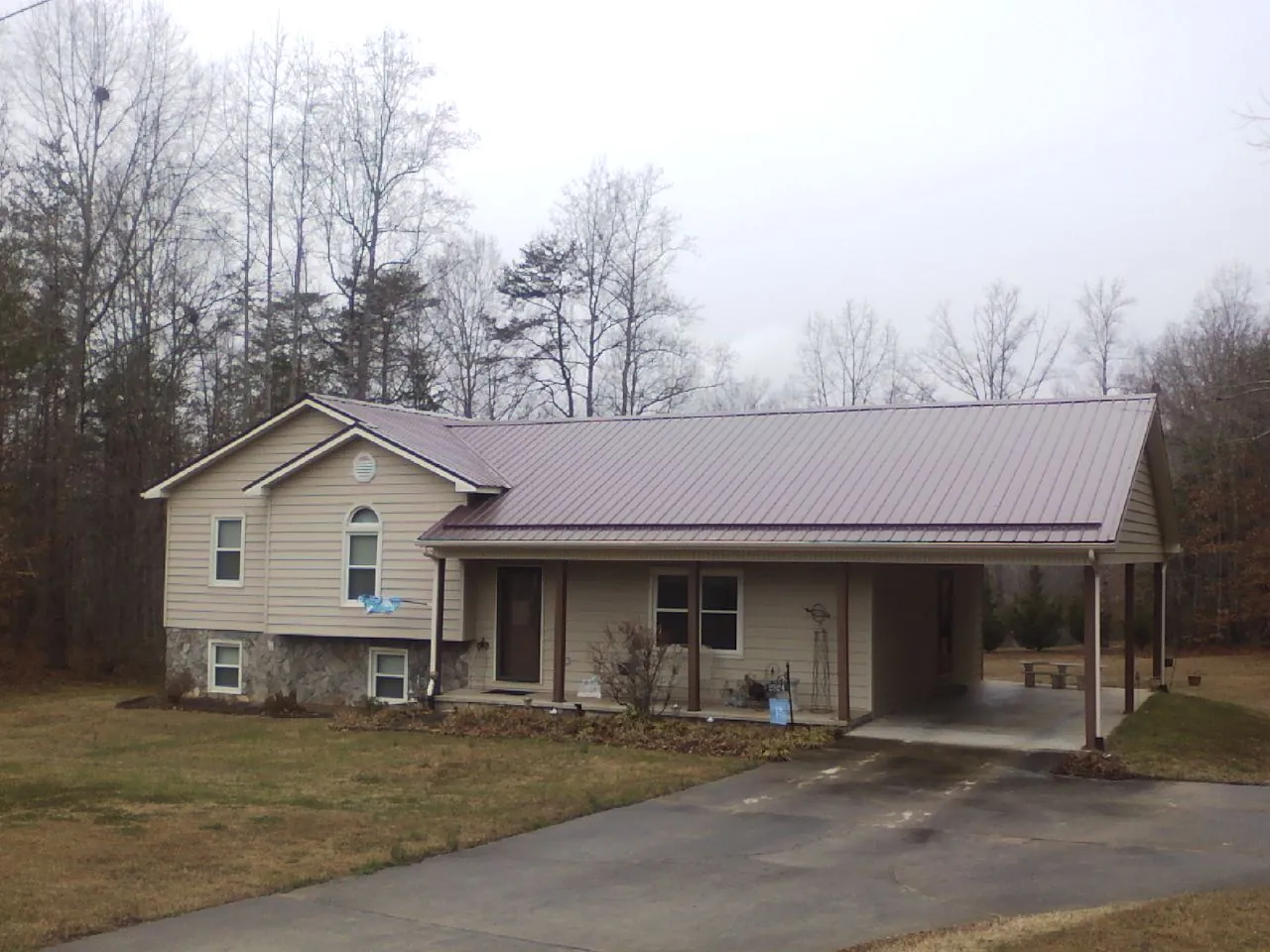 Burgundy metal roof on a tan split level home with an attached carport in Oregon