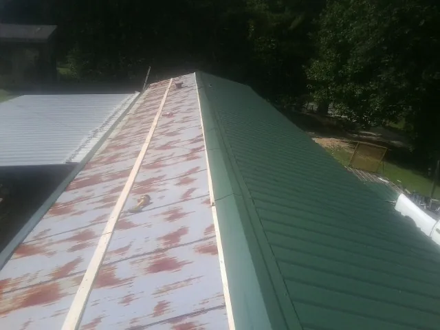 Old rusted panels beside newly installed green metal roofing — Wind Damage Roof Repair by Roofing Brothers in Oregon