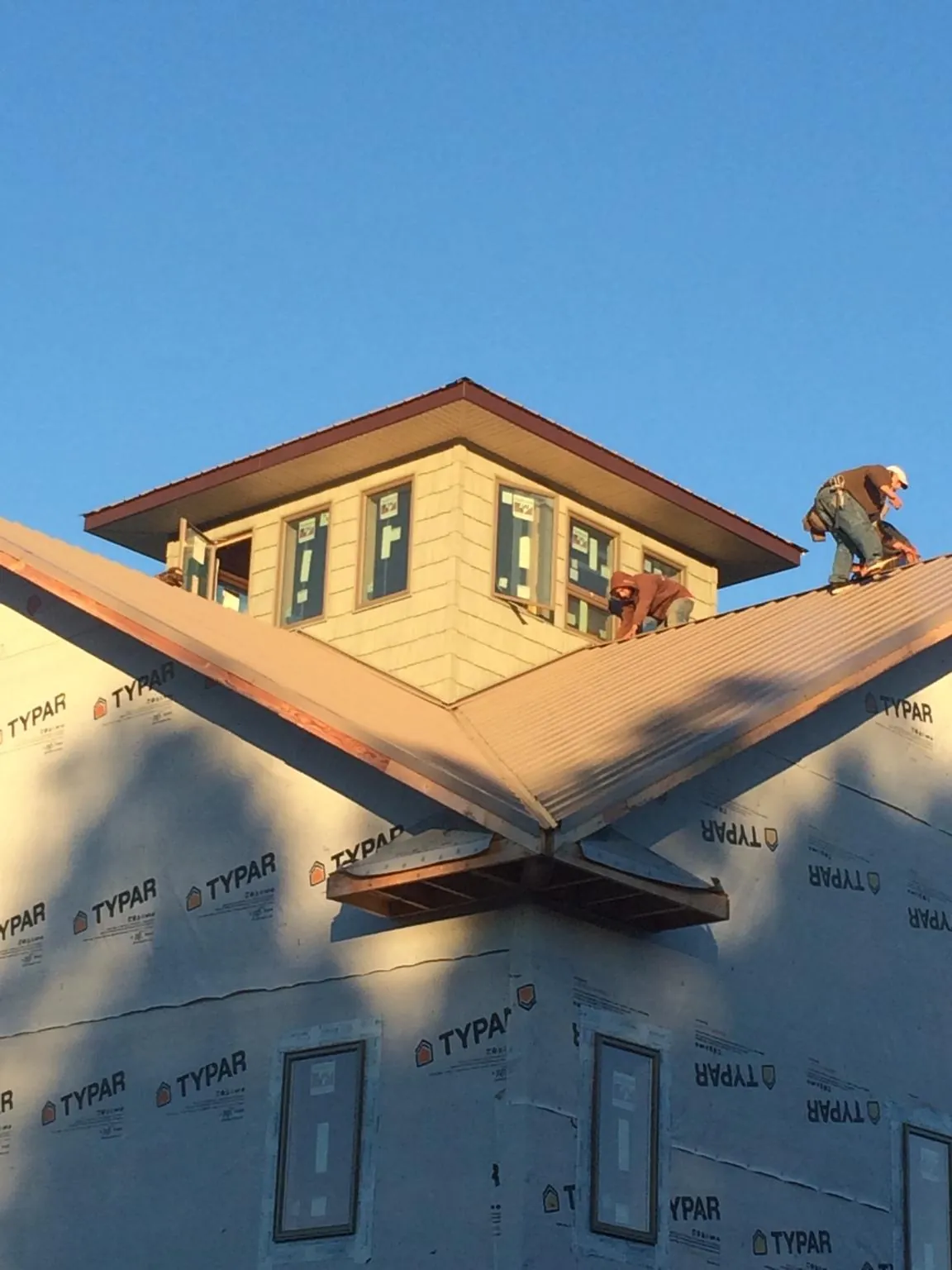 Roofers working around a rooftop cupola on a new metal roof at sunset — Roof Waterproofing in Oregon by Roofing Brothers